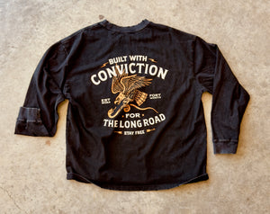 Black long-sleeve shirt with eagle graphic and text on a concrete surface