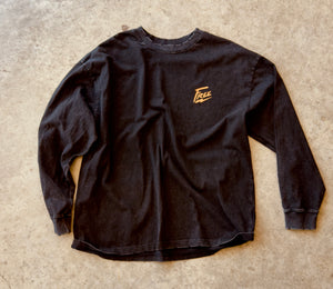 Black long-sleeve shirt with a logo on a beige surface