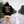 Person wearing a black hoodie with text and graphics, standing on a road flanked by trees.