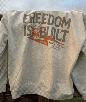 Gray sweatshirt with 'Freedom is Built' graphic on a textured surface