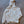Beige hoodie with a logo on the back, laid flat on a concrete surface
