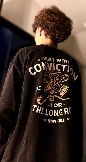 Person wearing a black long sleeve with text and an eagle design on the back.