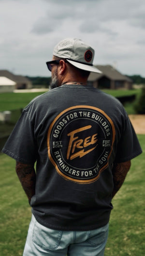 Man wearing a gray t-shirt with a orange and black logo outdoors
