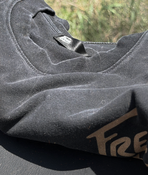 Close-up of a gray hoodie with a brand logo on a blurred natural background