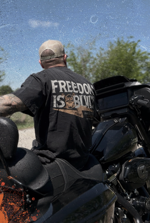 Man sitting on a motorcycle wearing a t-shirt with 'Freedom is Built' text.